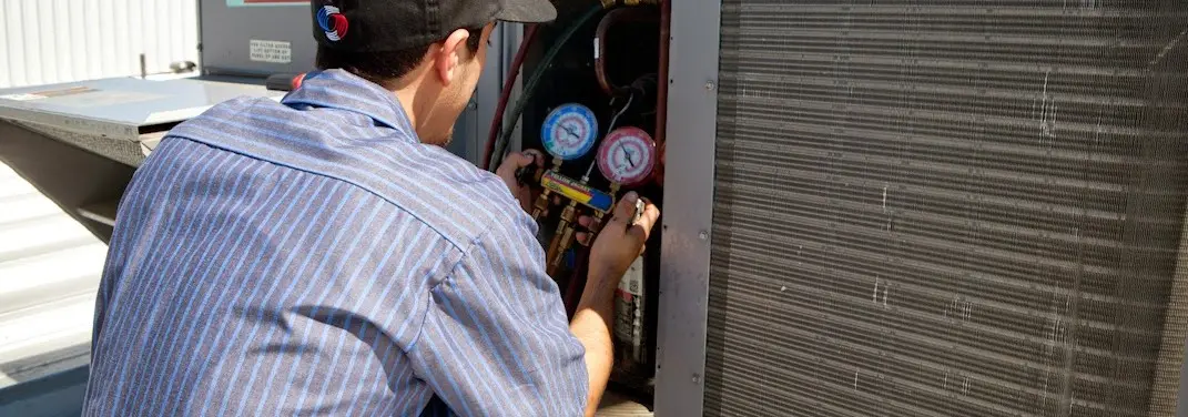 HVAC technician servicing a condenser unit in Lindale